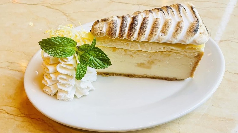 A slice of The Cheesecake Factory's Lemon Meringue Cheesecake is shown.
