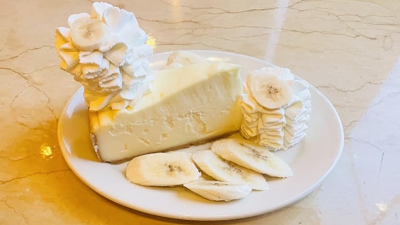 A slice of The Cheesecake Factory's Fresh Banana Cream Cheesecake is shown.