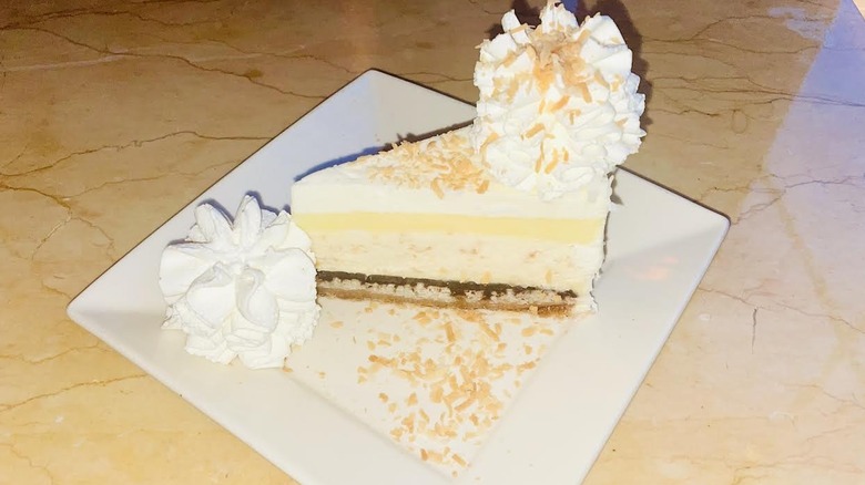 A slice of The Cheesecake Factory's Coconut Cream Pie Cheesecake is shown.