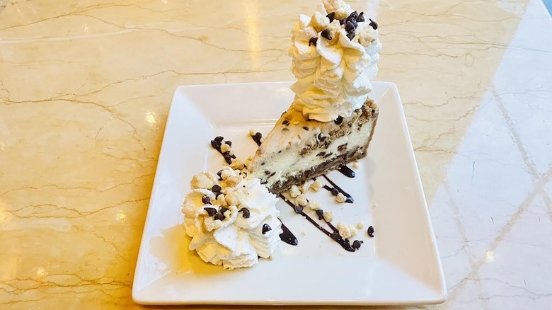 A slice of The Cheesecake Factory's Cookie Dough Lover's Cheesecake with Pecans is shown.