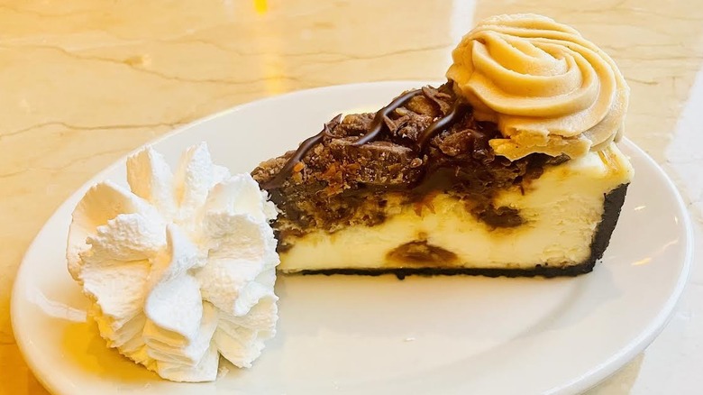 A slice of The Cheesecake Factory's Adam's Peanut Butter Cup Fudge Ripple Cheesecake is shown.