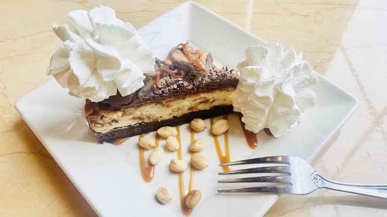 A slice of The Cheesecake Factory's Chocolate Caramelicious Cheesecake Made with Snickers is shown.
