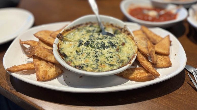 Olive Garden Spinach-Artichoke Dip in dish with flatbread crisps on table