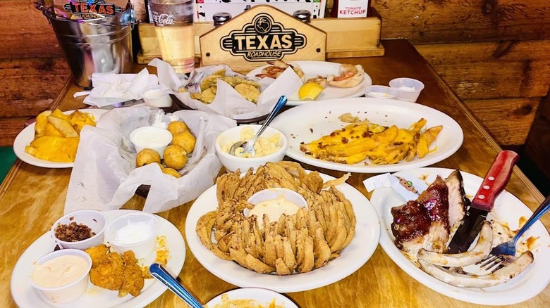 A table is full of partially eaten Texas Roadhouse appetizers.