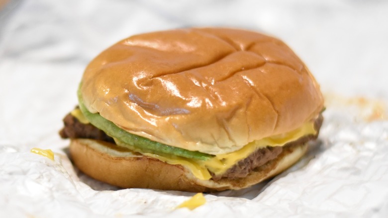 A burger with cheese and lettuce on a buttery bun