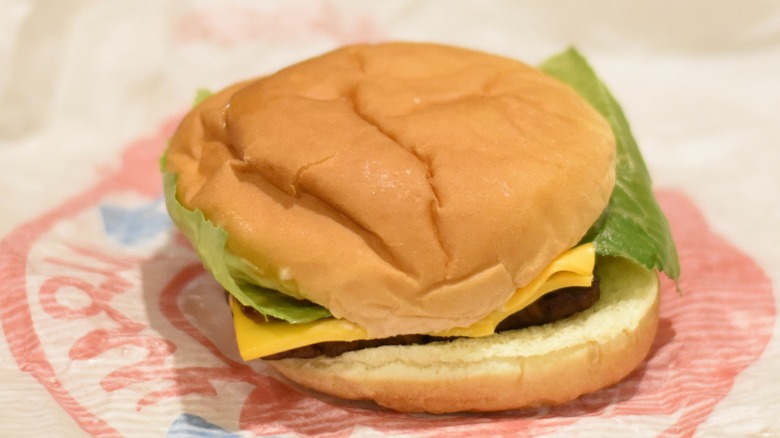 A burger with cheese and lettuce on a bun