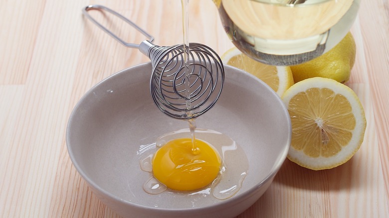 Egg yolk in a bowl with mayo ingredients.