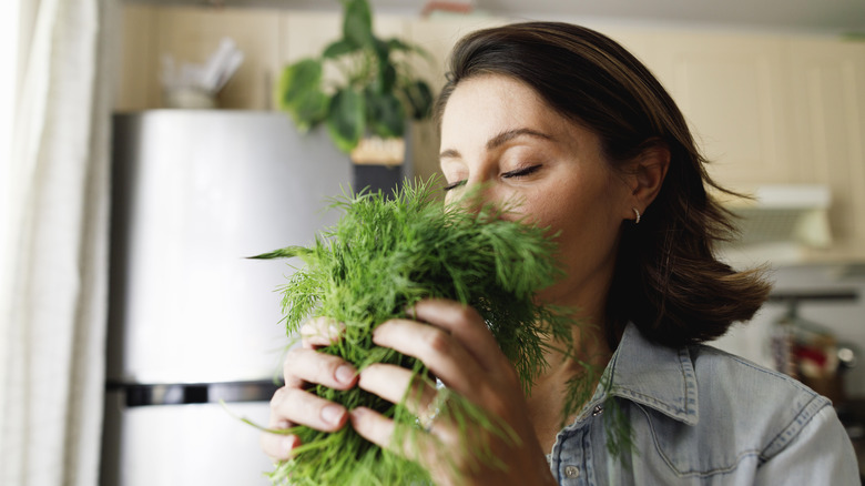 woman smelling dill in kitchen