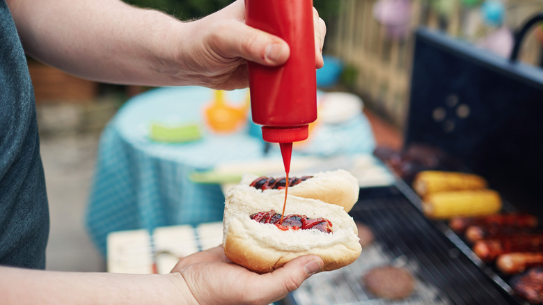 squeezing ketchup on hot dog