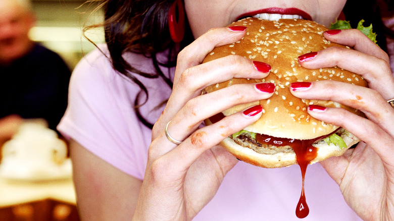 woman eating burger with ketchup