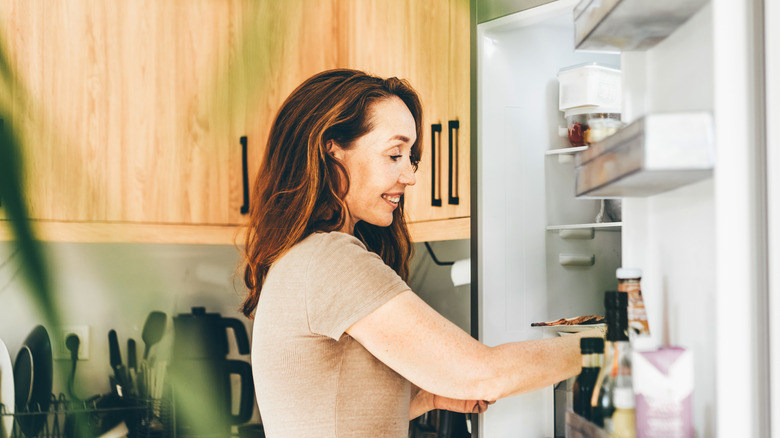 Woman removing food from refrigerator