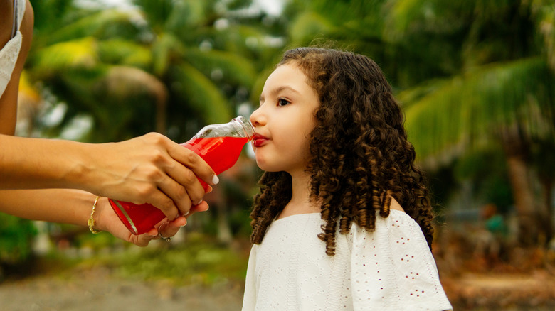 Child being fed soft drink