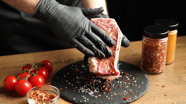 hands rubbing spices on steak