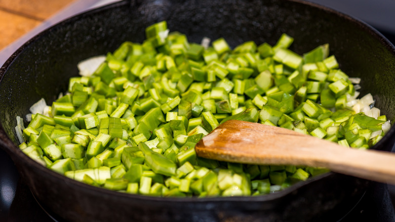 Nopales cooking in a skillet with a wooden spoon