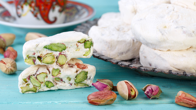 Iranian gaz is served on a blue table with tea surrounded by pistachios.