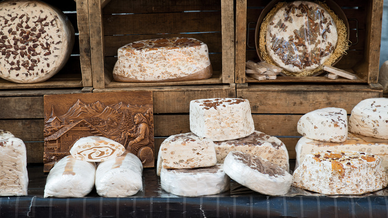 Assorted artisanal nougats are on display in wooden crates at a market in France.