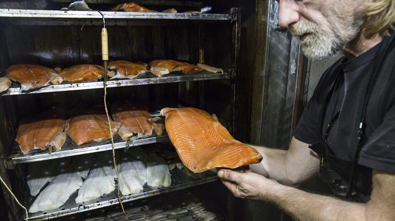 man taking fish fillet out of smoker