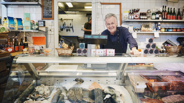 man smiling behind seafood counter at deli