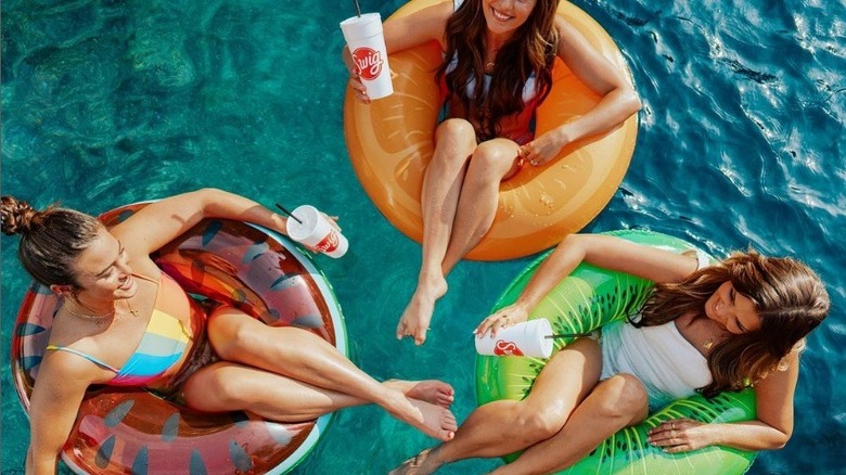 Three women on floats with Swig cups