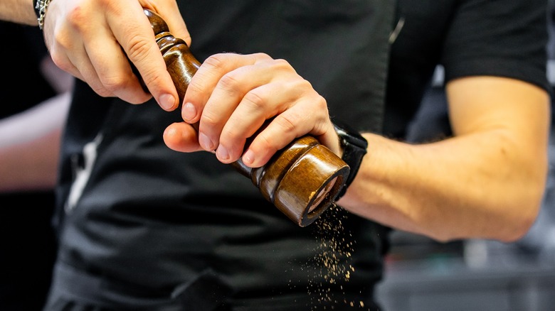 person grinding black pepper