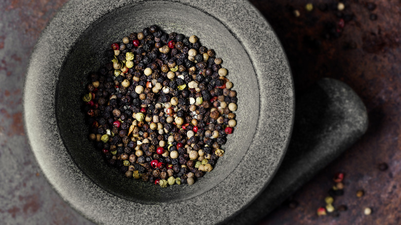 Various colored peppercorn in mortar