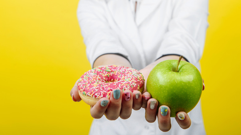 Person holding doughnut and apple