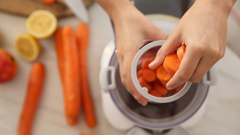 feeding carrot slices into juicer