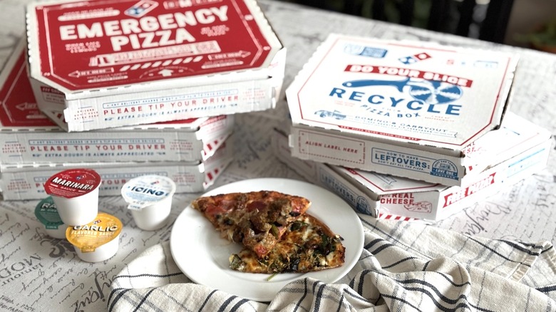 Domino's pizza boxes with plate of pizza and dipping sauces