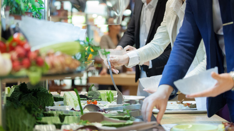 People serving themselves at salad bar