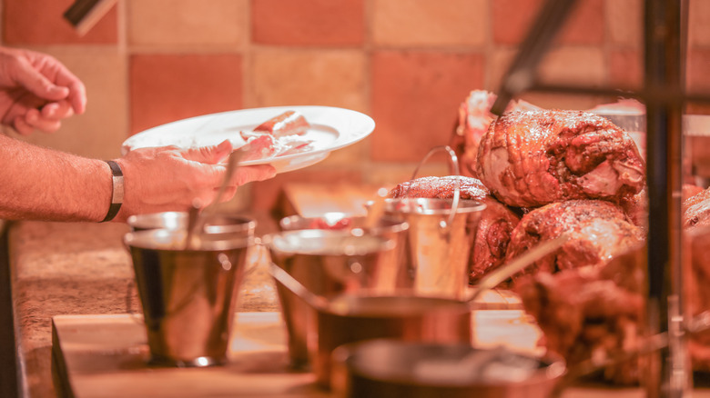 Man holding plate waiting to be served at buffet