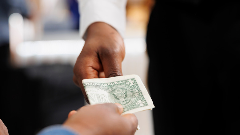 Person giving cash tip to server