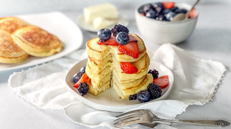 Fluffy lemon ricotta pancakes in stack on plate with berries