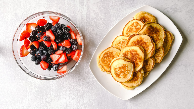 Fluffy lemon ricotta pancakes on platter with berries in bowl