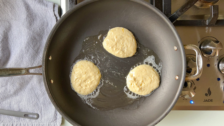 Fluffy lemon ricotta pancakes cooking in skillet