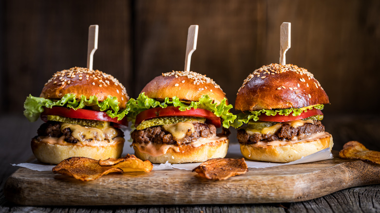 Three cheeseburgers on wooden board