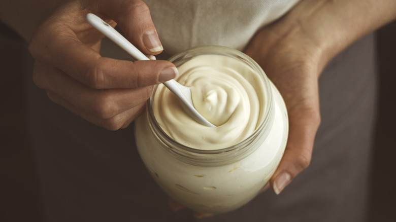 person putting spoon in mayonnaise