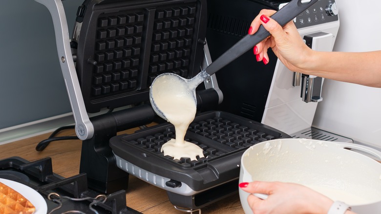 hand pouring waffle batter