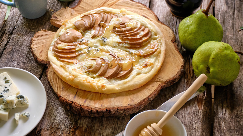 Pear and blue cheese pizza on top of a wooden tray.