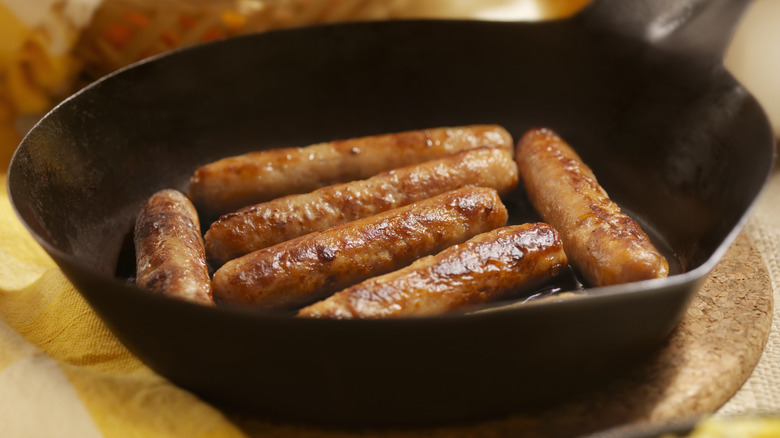 breakfast sausage links cooking in a cast iron pan