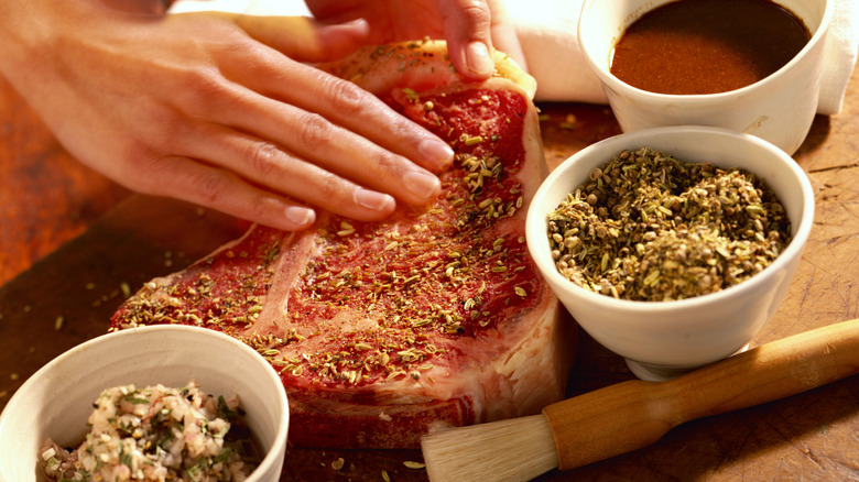 A person rubbing seasoning onto a steak