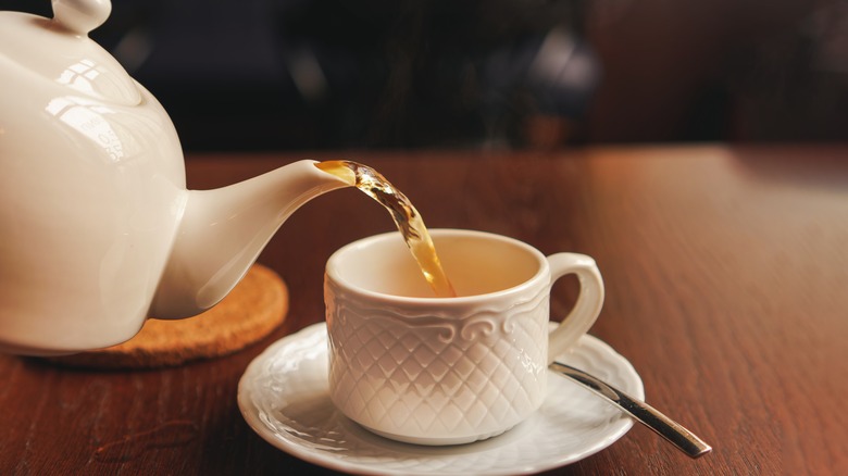 Teapot pouring tea into cup