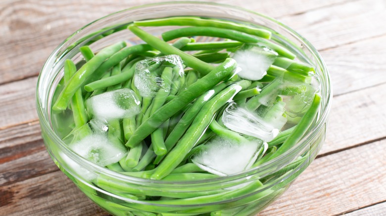 string beans in clear glass bowl of ice water