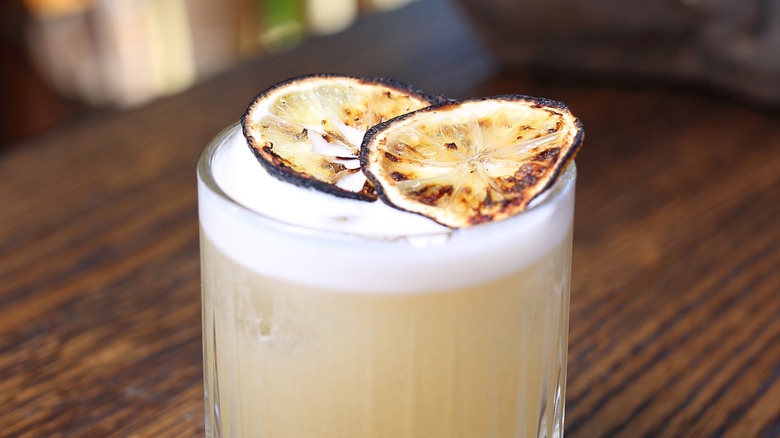 A whiskey sour with a grilled lemon garnish.