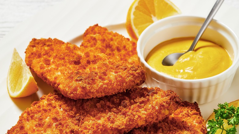 Fried fish on a plate with a side of mustard