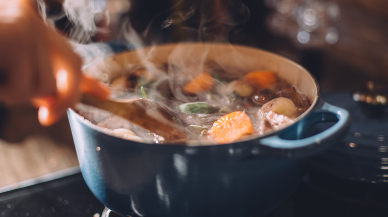 A hearty, steamy soup cooks on the stove in close-up.