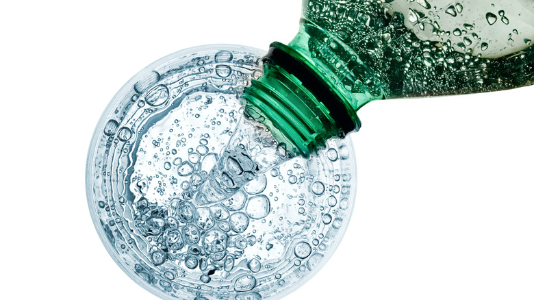 overhead of pouring soda water into cup