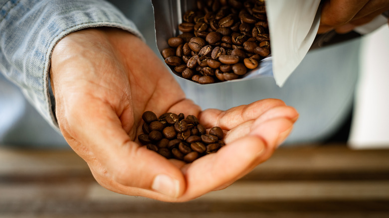 Person pouring coffee beans into their own hand