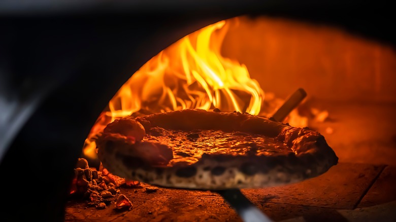 pizza being placed in wood fire oven