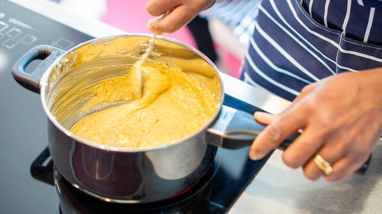 hands stirring roux in a pot