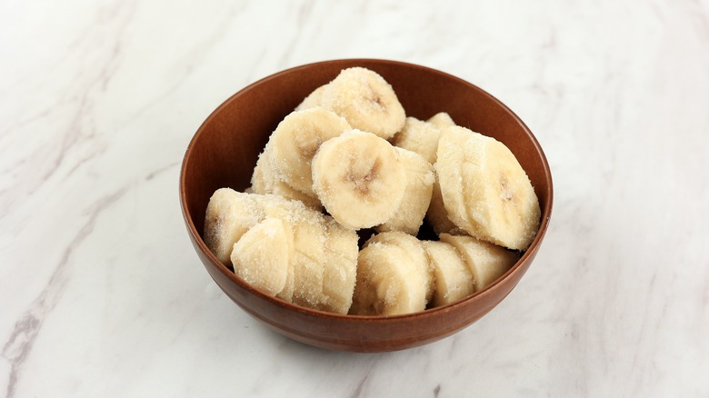 small brown wooden bowl filled with frozen banana slices